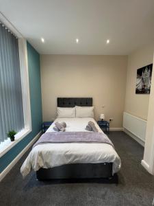 um quarto com uma cama grande e paredes azuis em Edgerton Suites em Huddersfield