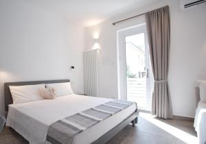 - une chambre blanche avec un lit et une porte coulissante en verre dans l'établissement Casa Maluna, à La Spezia