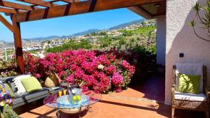 a patio with pink flowers and a glass table at Casa ideal para famílias com vista mar desafogada in Funchal