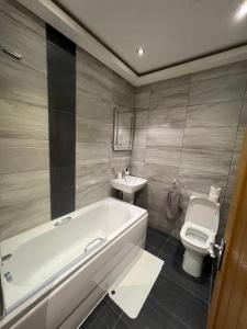 a bathroom with a tub and a toilet and a sink at Edgerton Suites in Huddersfield