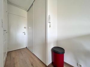 un corridoio con un bidone della spazzatura rosso e una porta di Studio confortable et lumineux proche des hôpitaux - Hotel de ville Beaumont a Beaumont