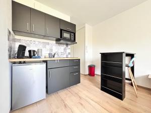 una cucina con mobili neri e un piano di lavoro di Studio confortable et lumineux proche des hôpitaux - Hotel de ville Beaumont a Beaumont