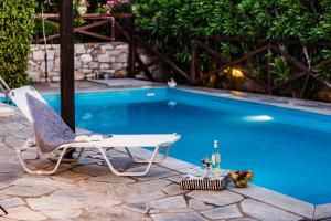 a chair and a bottle of wine next to a swimming pool at Villa 10 Elies in Koropi