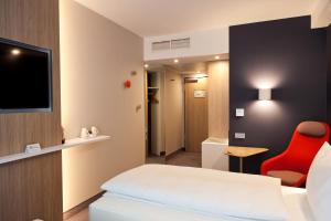 a hotel room with a bed and a red chair at Holiday Inn Express Bochum, an IHG Hotel in Bochum