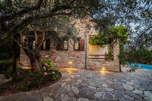 a brick house with a tree and a stone driveway at Villa 10 Elies in Koropi