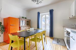 a kitchen with a black table and yellow chairs at Appartements de l'Abbaye - A 10 minutes de Disneyland in Lagny