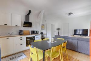 a kitchen and living room with a table and yellow chairs at Appartements de l'Abbaye - A 10 minutes de Disneyland in Lagny