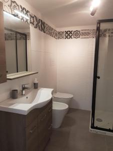 een badkamer met een wastafel, een toilet en een spiegel bij Kamarinè - sul mare in Scoglitti