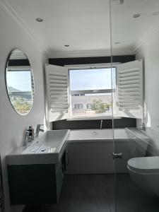 uma casa de banho com um lavatório, um WC e uma janela. em The Atlantic DonReal Guesthouse na Cidade do Cabo