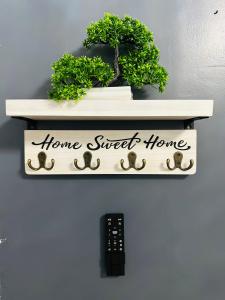 a shelf with a home sweet home sign and a remote control at Cozy Guest House 1.9 miles from Hard Rock Stadium in Miami Gardens