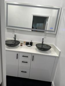 a bathroom with two sinks and a mirror at Cozy Guest House 1.9 miles from Hard Rock Stadium in Miami Gardens