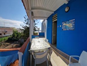 a balcony with a table and chairs on a blue wall at Case Pescatori in Lampedusa