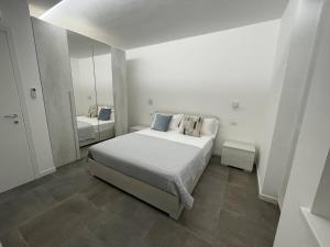 a white bedroom with a bed and a mirror at IseoLakeRental - Casa Il Nido in Fonteno