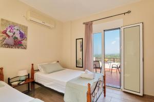 a bedroom with two beds and a view of a balcony at Exclusive Villa - Amazing View & Private Pool in Agia Triada