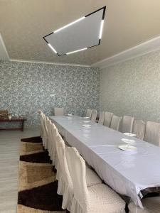 una sala de conferencias con una mesa larga y sillas blancas en Гостевой Домик Жайлау, en Taraz