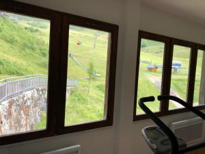 a room with three windows with a view of a playground at Appartement 4 personnes aux pieds des pistes, Ariège in Ustou