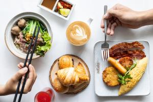 a white table with plates of food and two people holding chopsticks at Lynnaya Urban River Resort in Siem Reap