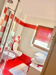 baño rojo y blanco con aseo y ventana en CASA MARILU', en Castello di Fiemme