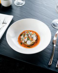 a white plate with a dish of food on a table at MOLO LIPNO RESIDENCE in Lipno nad Vltavou