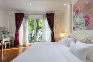 a bedroom with a large white bed and a desk at My Moon Hotel Hanoi in Hanoi