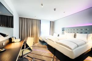 Premier Inn Darmstadt City Centre في دارمشتات: غرفه فندقيه ثلاث اسره ومكتب