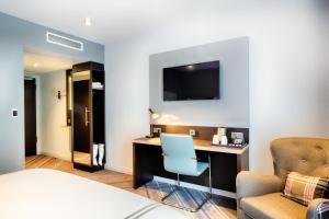 a hotel room with a desk and a tv on the wall at Premier Inn Darmstadt City Centre in Darmstadt