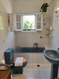 a bathroom with a blue tub and a toilet and a sink at Olive Hill House in Vragkaniótika