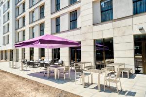 un bâtiment avec des tables, des chaises et un parasol violet dans l'établissement Premier Inn Darmstadt City Centre, à Darmstadt