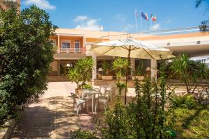 a patio with an umbrella and a table and chairs at Hotel Avenida in Benic&agrave;ssim