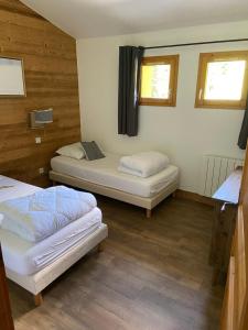 two beds in a room with wooden walls and windows at Appartement duplex 8 à 10 personnes - Belle Plagne - Pieds de pistes in La Plagne Tarentaise +25 photos