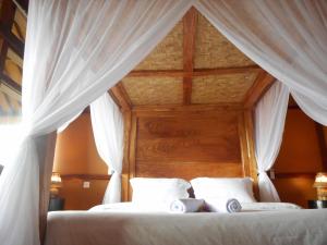 a bedroom with a canopy bed with white curtains at Villa Dukuh in Selat