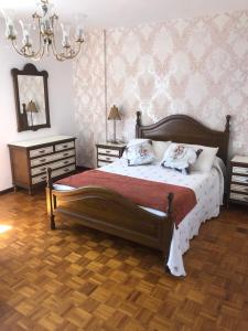 een slaapkamer met een groot bed en een kroonluchter bij Apartamento céntrico en la playa de Bueu in Bueu