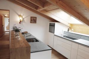 eine Küche mit weißen Schränken und einer Holzdecke in der Unterkunft Hotel Sarain Active Mountain Resort in Lenzerheide
