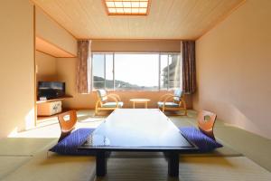 Cette chambre dispose d'une grande fenêtre et d'une table avec des chaises. dans l'établissement Ooedo Onsen Monogatari Hotel Kinugawa Gyoen, à Nikkō