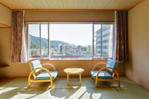 日光市にある大江戸温泉物語 ホテル鬼怒川御苑の椅子2脚とテーブル、大きな窓が備わる客室です。