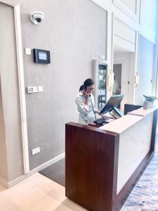 una mujer hablando por un celular en una oficina en Address Beach Resort Fujairah Apartment 2 Bed Rooms and Small Bed Room - Ground Floor 3011, en Al Aqah