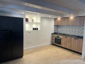 a kitchen with a black refrigerator and wooden cabinets at Loft Marconi 34 in Soverato Marina