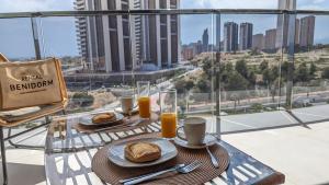 una mesa con 2 platos de comida en el balcón en SUNSET WAVES sun & beach apartments en Benidorm