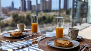 una mesa con dos platos de comida y dos vasos de zumo de naranja en SUNSET WAVES sun & beach apartments en Benidorm