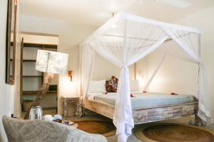 a bedroom with a bed with a canopy at Mr Kahawa Waterfront Suites in Paje