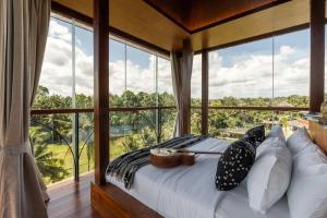 Bett in einem Zimmer mit einem großen Fenster in der Unterkunft Soulshine Bali in Ubud