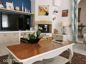 ein Wohnzimmer mit einem TV und einem Tisch in der Unterkunft Maison de vacances in Bédarrides