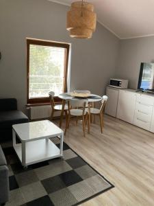 a living room with a table and chairs and a kitchen at Apartament w Parku Planty in Elblag