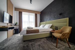 a bedroom with a bed and a chair and a television at GBU Home Timisoara in Timişoara
