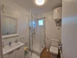 uma casa de banho com um chuveiro, um WC e um lavatório. em Apartmani Natalija 4 stars em Mrljane