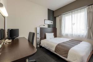 a hotel room with a bed and a desk with a computer at Comfort Hotel Koriyama in Koriyama