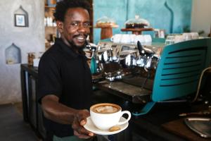 un hombre sosteniendo una taza de café en una cafetería en Mr Kahawa Lofts en Paje