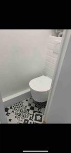 La salle de bains est pourvue de toilettes et d'un sol noir et blanc. dans l'établissement Cosy Studio - Pyrénées, à Paris