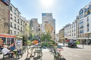une rue de la ville avec des tables, des chaises et des bâtiments dans l'établissement Cosy Studio - Pyrénées, à Paris