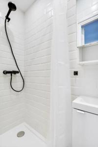 La salle de bains blanche est pourvue d'une douche et d'un lavabo. dans l'établissement Cosy Studio - Pyrénées, à Paris